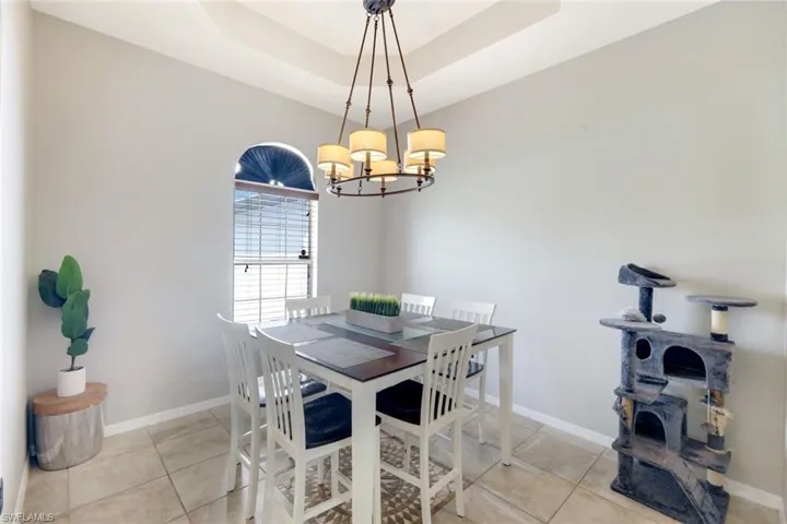 Dining room with a raised ceiling, light tile patterned flooring, and a chandelier