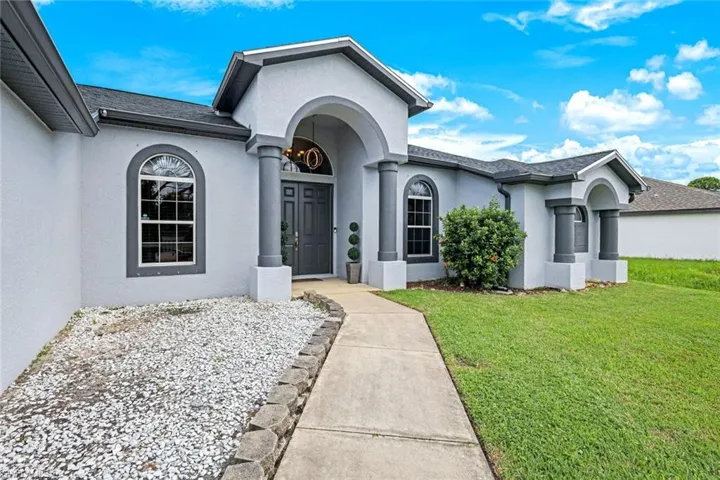 Property entrance featuring stucco siding and a yard