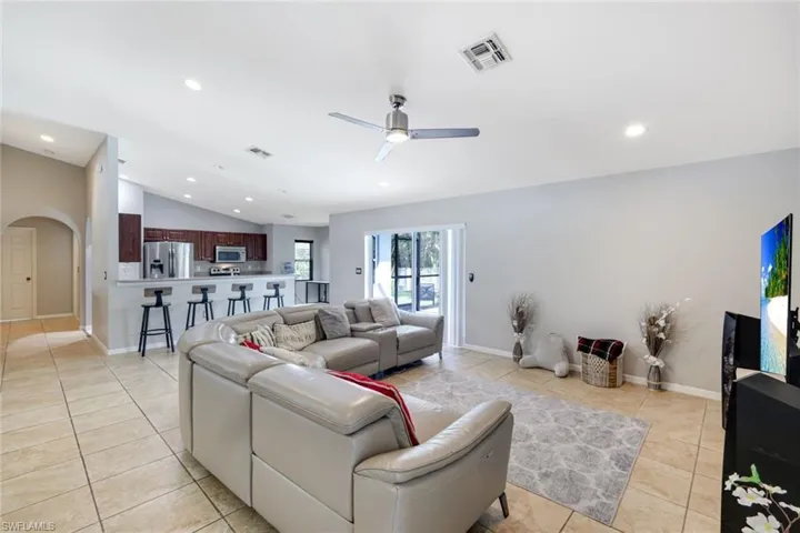 Living area featuring arched walkways, vaulted ceiling, recessed lighting, light tile patterned floors, and a ceiling fan