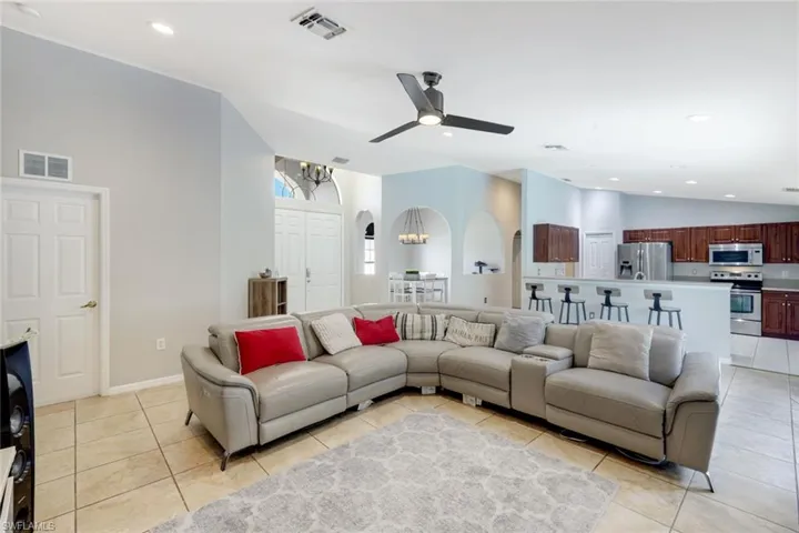 Living area with arched walkways, lofted ceiling, recessed lighting, light tile patterned floors, and a ceiling fan