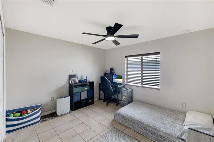 Bedroom featuring tile patterned floors, ceiling fan, and an office area