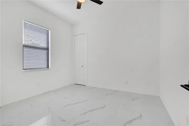 Spare room featuring light marble finish floors and ceiling fan