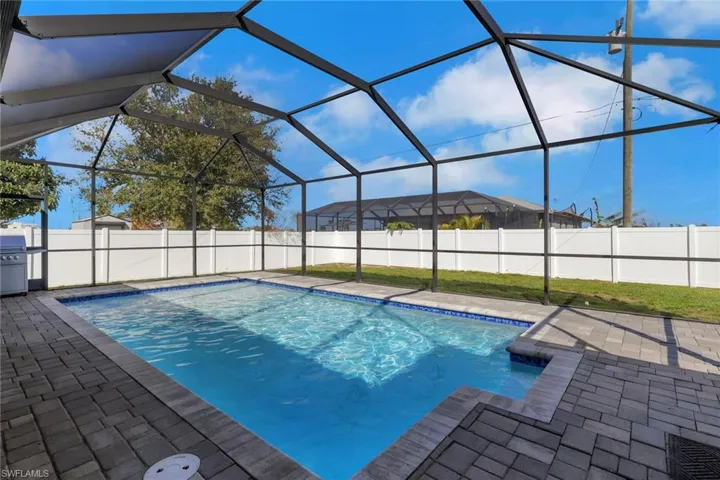 View of pool featuring a fenced backyard, a sunroom, glass enclosure, area for grilling, and patio surround
