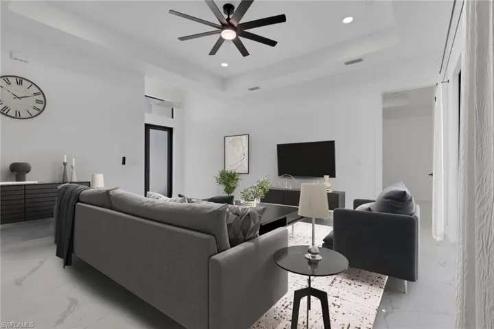 Living area with a tray ceiling, recessed lighting, a ceiling fan, and light marble finish flooring