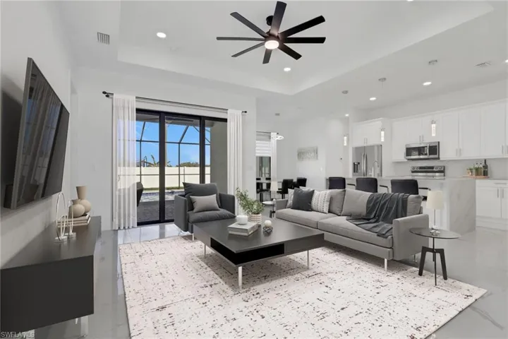 Living area with ceiling fan, a raised ceiling, and recessed lighting