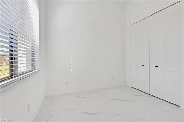 Unfurnished bedroom with a closet and light marble finish floors