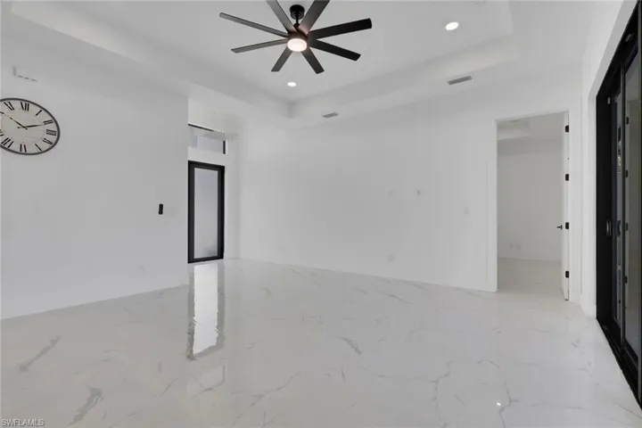 Unfurnished room with a tray ceiling, recessed lighting, a ceiling fan, and light marble finish flooring