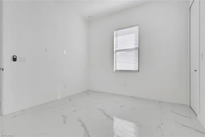 Spare room with light marble finish flooring and baseboards