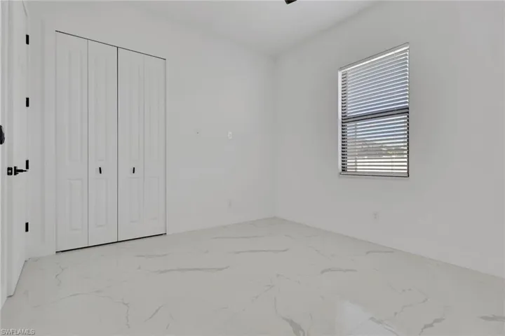Unfurnished bedroom featuring light marble finish flooring, a closet, and ceiling fan
