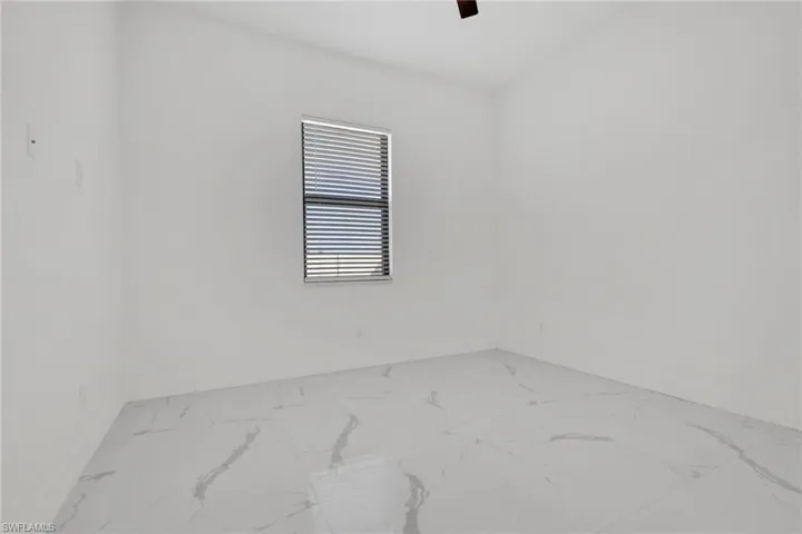Empty room with marble look tile flooring and a ceiling fan