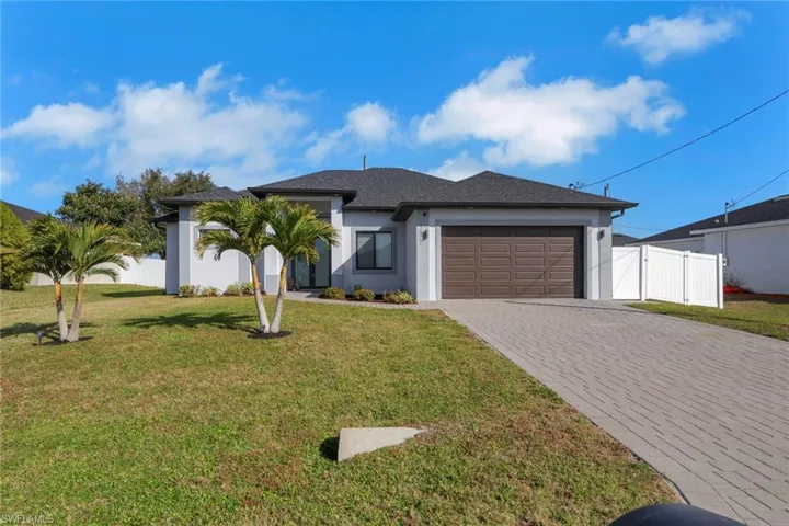 View of front of property with a garage, decorative driveway, stucco siding, and a gate