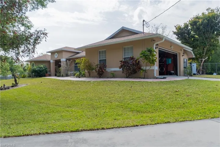 View of front of home with stucco siding, a front lawn, and an attached garage