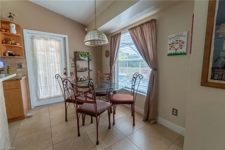 Dining space featuring light tile patterned flooring, baseboards, and lofted ceiling