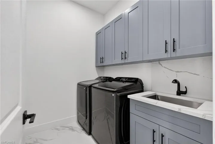 Laundry room: washer, dryer, sink and cabinets