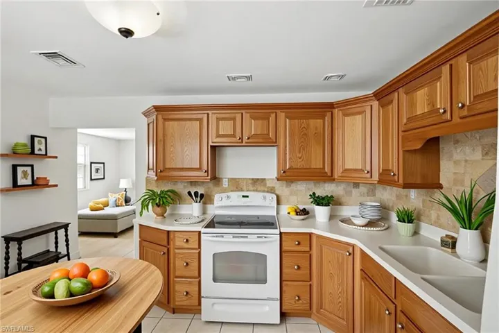 Kitchen featuring white range with electric cooktop, light countertops, backsplash, and a sink