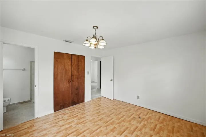 Unfurnished bedroom featuring a chandelier, wood finished floors, a closet, and baseboards