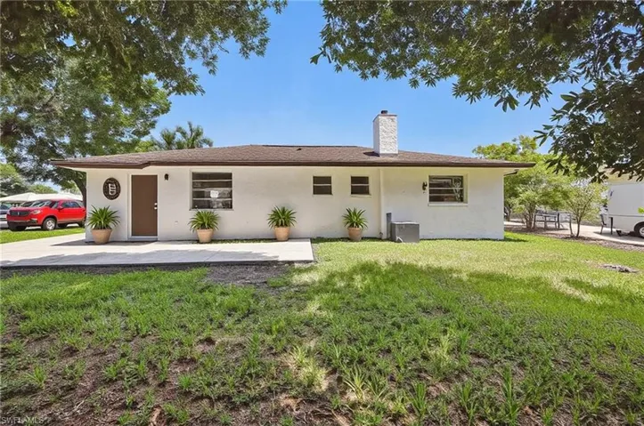 Back of house featuring stucco siding, a yard, and a patio