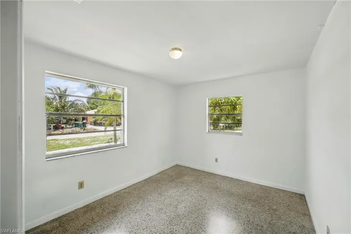 Unfurnished room with healthy amount of natural light, baseboards, and speckle patterned floor
