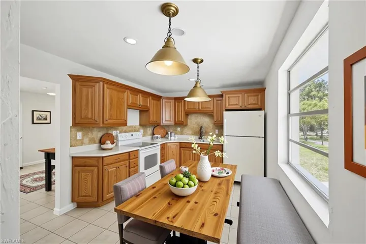 Kitchen featuring white appliances, light tile patterned floors, tasteful backsplash and plenty of natural light