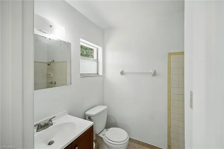 Full bathroom featuring vanity, toilet, tiled shower, and tile patterned floors