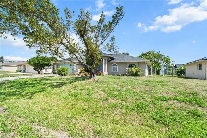 Single story home featuring an attached garage, stucco siding, and a front lawn