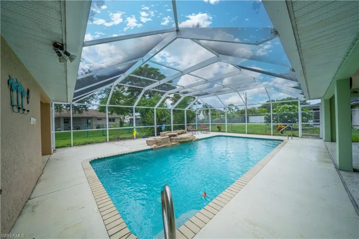 View of swimming pool with a patio and glass enclosure