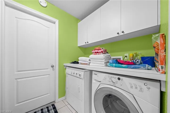 Laundry room featuring washer and clothes dryer, cabinet space, and light tile patterned floors