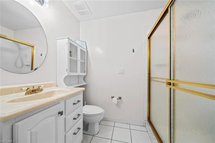 Full bath with toilet, vanity, a stall shower, tile patterned floors, and baseboards