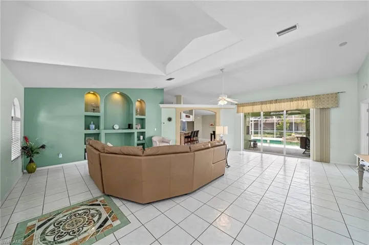 Living area with light tile patterned flooring, vaulted ceiling, and a ceiling fan