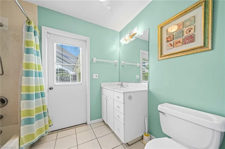 Bathroom featuring vanity, tile patterned flooring, toilet, shower / bath combination with curtain, and baseboards