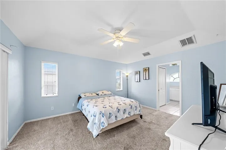 Bedroom with light carpet, multiple windows, and baseboards