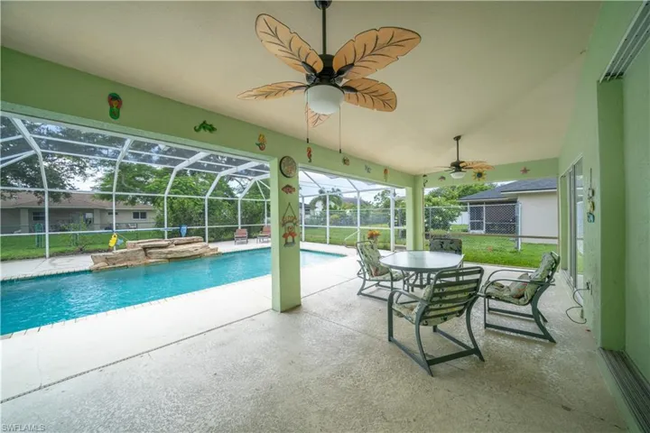 View of pool with a patio area, ceiling fan, glass enclosure, and a yard