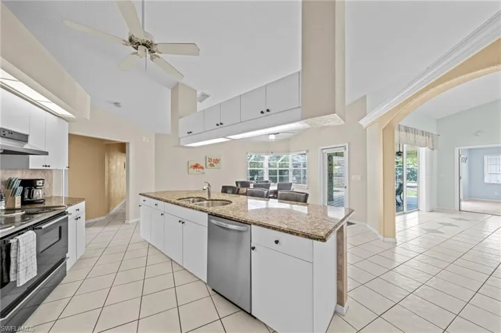 Kitchen with dishwasher, black / electric stove, a sink, light tile patterned floors, and high vaulted ceiling