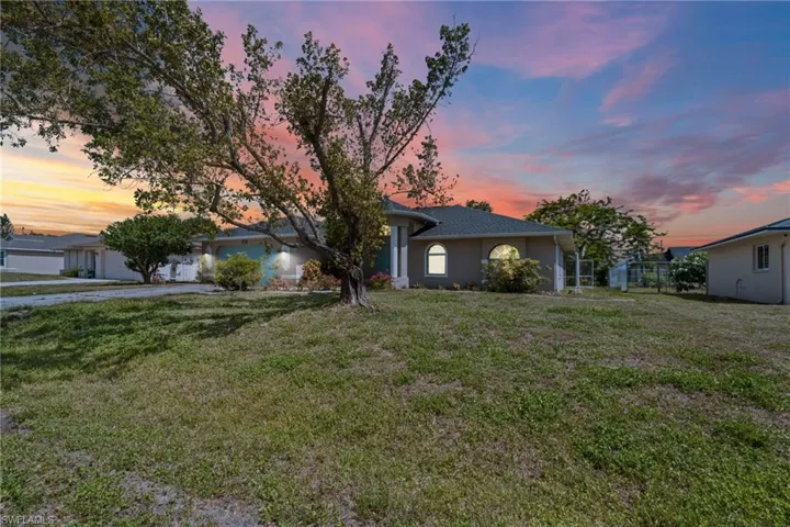 Single story home with a garage, a front lawn, asphalt driveway, and stucco siding