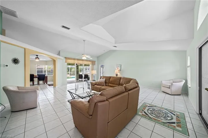 Living room featuring a ceiling fan, light tile patterned floors, and vaulted ceiling