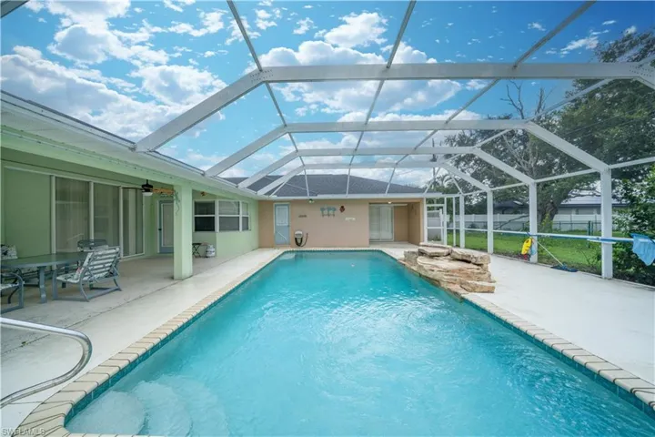 View of pool with a patio area, ceiling fan, and a lanai