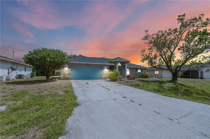 Ranch-style house featuring driveway, a garage, a yard, stucco siding, and central AC