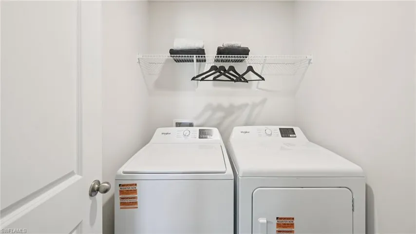 Model Home. Dedicated laundry area featuring a washer and dryer, along with a wall-mounted wire shelf for storage