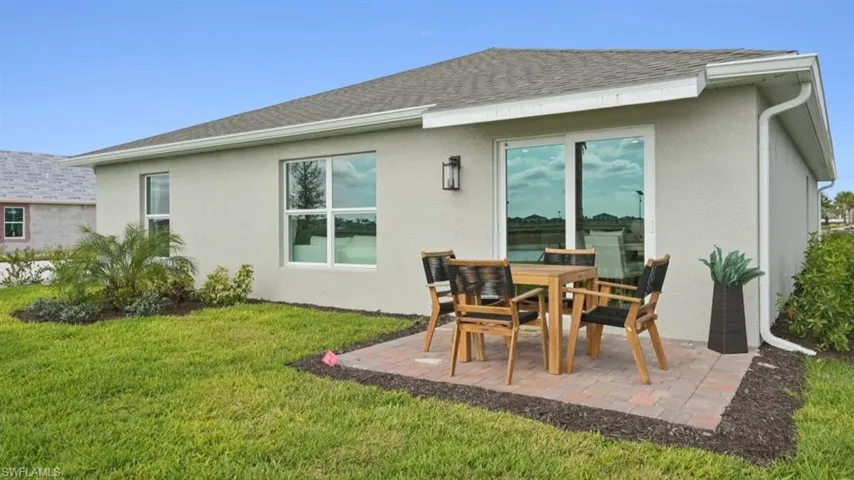 Model Home. The property features a private patio with brick pavers, a well-maintained lawn, and a large sliding glass door