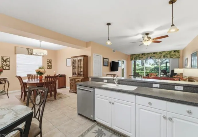 Kitchen with decorative light fixtures, white cabinets, open floor plan, dishwasher, and a ceiling fan
