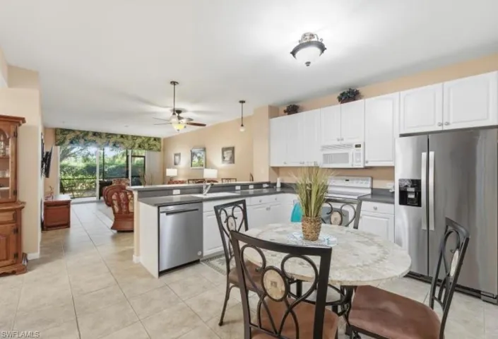 Kitchen with appliances with stainless steel finishes, dark countertops, a peninsula, white cabinets, and light tile patterned floors