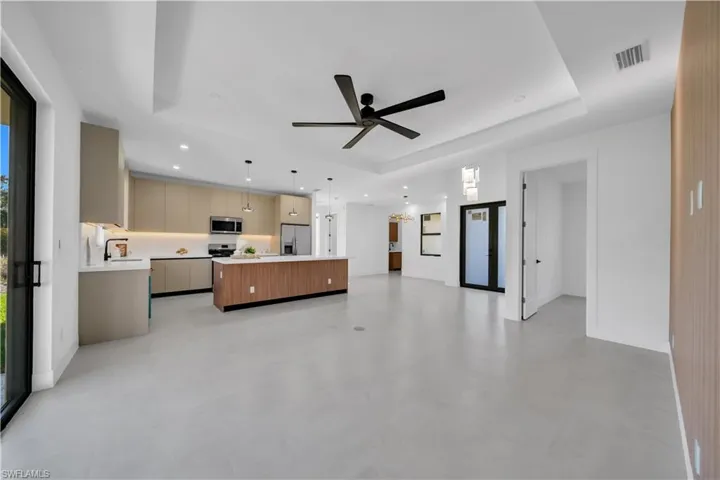 Open concept living space featuring a contemporary kitchen with a large island, stainless steel appliances, and sleek cabinetry