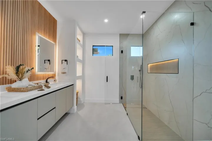 Walk-in shower with full height stone-look wall panels and an illuminated recessed niche