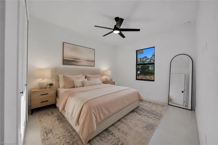 Bedroom featuring a black ceiling fan with integrated lighting, a large window, and white walls