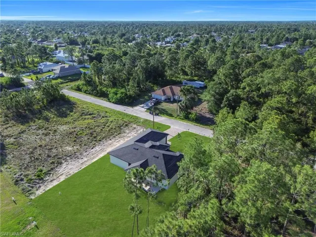 New construction residence featuring a dark shingle roof and light-colored siding, situated on a manicured lawn