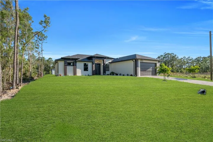 Contemporary single-story residence featuring a two-tone exterior, dark trim windows, and an attached two-car garage with a modern door