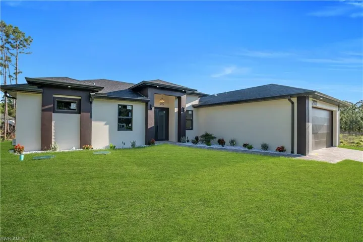 Contemporary exterior featuring a stucco finish, dark trim accents, a paver driveway, an attached two-car garage, and a covered entry with an overhead light fixture