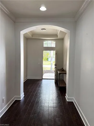 Entryway featuring arched walkways, ornamental molding, hardwood / wood-style floors, and a tray ceiling