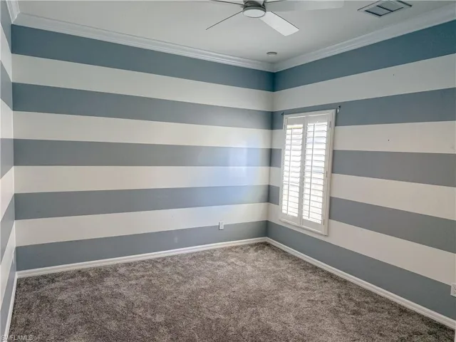 Spare room with ornamental molding, carpet floors, and ceiling fan