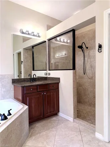 Full bath featuring vanity, walk in shower, a garden tub, and light tile patterned floors